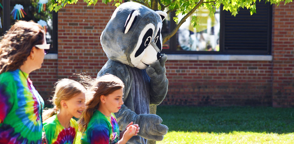 Students running with Roger the Racoon at Fun Run